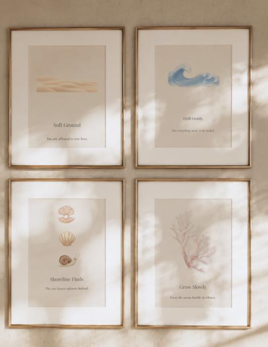 Close-up of the Coastal Calm Collection featuring four neutral coastal printable artworks in matching oak frames with soft natural sunlight across the gallery wall.